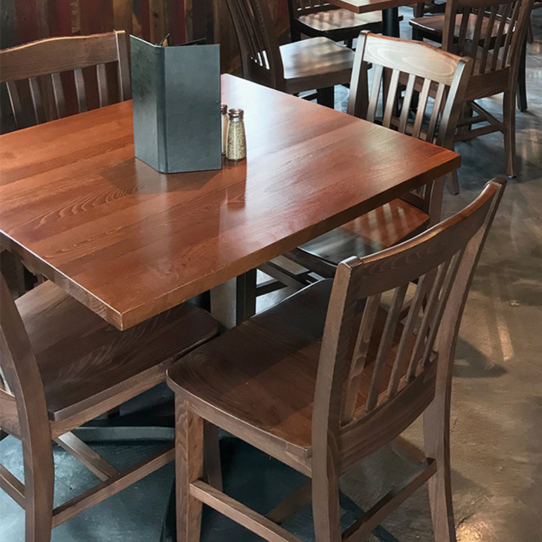 A wooden dining table set in a restaurant with mixed chair styles.